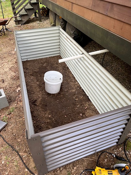 Raised mulch basin under construction next to tiny home on wheels
