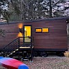 Modern cedar-clad tiny house on wheels at dusk